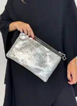 Cartera tipo sobre con lentejuelas doradas y negras reversibles, con borde superior de cuero negro y correa fina de cuero negro.