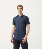 Camisa azul de manga corta con cuello clásico, corte slim fit, cierre frontal con botones blancos y bolsillo de parche en el pecho.