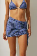 Falda corta tipo pareo con diseño de rayas verticales en tonos azul y negro. Presenta un lateral fruncido con cordón ajustable que permite regular el largo y el ajuste de la prenda.
