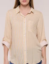 Camisa de rayas finas verticales en tonos amarillo y blanco, de corte clásico y silueta holgada. Cuenta con cuello camisero, cartera frontal de botones, un bolsillo plaqué en el pecho con rayas horizontales a contraste, mangas largas con presilla y ruedo curvo.