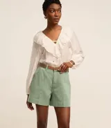 Short de mujer de sarga color beige claro, tiro alto, con pespunte contrastante en color blanco o crema. Presenta un corte regular y bolsillos delanteros y traseros.