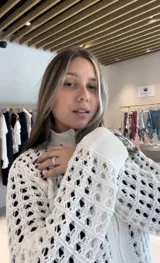 Chaqueta de punto calado color azul marino, con cierre frontal completo, cuello alto y puños tejidos en punto elástico.