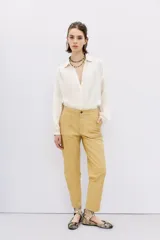 Pantalon de corte recto confeccionado en cuero ovino con acabado metalizado en color plata. Presenta cierre frontal con cremallera y bolsillos laterales.