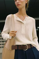 Bolso de hombro color tostado con diseño estructurado que combina paneles de cuero liso y gamuza con pespuntes visibles. Cuenta con un asa larga de hombro ajustable y cierre superior con botón imantado.
