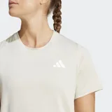 Remera de entrenamiento Adidas color beige, con cuello redondo, mangas cortas y las icónicas tres rayas de la marca en los laterales. Presenta el logo de Adidas estampado en el pecho y tecnología de absorción de humedad.