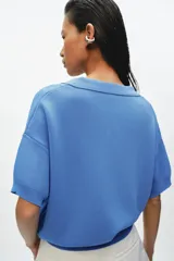 Polo amplio de punto color celeste, con cuello y escote en V, de manga corta.