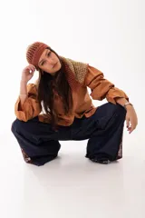 Capucha tejida a mano con diseño calado en tonos tierra, con tiras largas para atar.