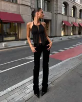 Top negro halter con diseño fruncido, escote pronunciado con tiras para atar y dobladillo asimétrico.
