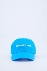 Gorra azul vibrante con visera curva y el texto "common edit" bordado en blanco en la parte frontal.