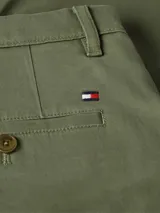 Pantalón chino verde oliva de Tommy Hilfiger, corte recto, confeccionado en satén de algodón ligeramente elástico, con cierre de cremallera y botón, bolsillos ribeteados en la cintura y bolsillos traseros de ojal con botón.