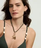 Top de bikini triangular color verde oscuro, con breteles finos adornados con cuentas blancas y negras.