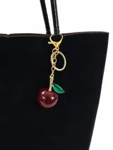 Llavero para bolso con diseño de cereza, compuesto por una pieza de resina roja con glitter, tallo y hoja esmaltada en verde, unido a una cadena y argolla metálica dorada.
