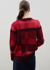 Sweater de punto con diseño jacquard a cuadros en tonos azul, marrón, crema y negro. Presenta cuello redondo, puños y ruedo acanalados, con un corte holgado y cómodo.