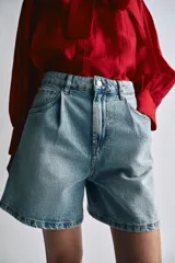 Shorts de denim de tiro alto y corte relaxed fit de Zara Woman Collection, en color celeste con lavado claro. Presenta trabillas en la cintura, cinco bolsillos, detalles de pliegues frontales y cierre con cremallera y botón metálico.