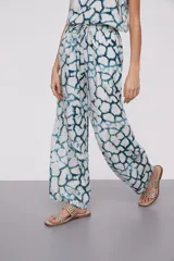 Pantalón largo de viscosa con estampado abstracto en tonos azules y blancos, cintura alta con cordón ajustable y corte ancho.