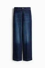 Jean ancho de tiro alto confeccionado en denim de algodón con ligero stretch, de color azul oscuro con efecto deslavado y pliegues frontales.