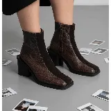 Bota Seul de cuero vacuno color marrón con textura tipo reptil combinada con paneles de gamuza, de caña alta, punta cuadrada y taco bloque de madera con folea de cuero. Cuenta con cierre lateral interno.