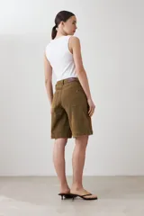 Bermuda de jean color verde oliva, corte a la rodilla, con bolsillos delanteros y traseros, y presillas para cinturón.