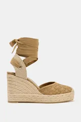 Sandalias de cuña color beige con capellada tejida y tiras de tela para atar al tobillo.