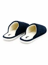 Pantufla abierta de pana azul marino con interior de corderito sintético color crema y suela plana.