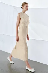 Vestido midi de viscosa con efecto arrugado, cuello redondo y diseño sin mangas. Presenta una sobrecapa superior con bordados detallados y entredoses, con cordones laterales ajustables terminados en borlas.