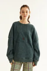 Buzo oversize de corte unisex, color rojo con efecto desgastado (acid wash), confeccionado en algodón con interior de polar. Presenta costuras frontales decorativas, hombros caídos, mangas largas con puños elastizados, rib en el cuello y el ruedo, y un pequeño logo bordado en el pecho.