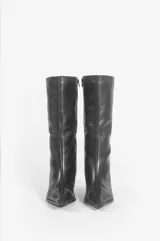 Bota de caña media confeccionada en cuero negro, con diseño de punta fina y taco bajo tipo kitten heel.