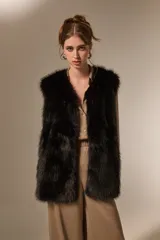 Chaleco sin mangas de piel sintética en color negro, con diseño abierto y corte recto.