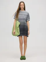 Vestido corto de punto con diseño degradado en tonos grises, cuello redondo y mangas cortas con puños a rayas en contraste.