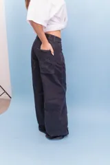 Pantalón de jean de corte wide leg en color gris oscuro, con tiro medio y cierre frontal con botón y cremallera.