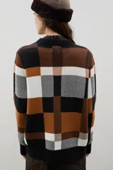 Sweater de punto con diseño jacquard a cuadros en tonos azul, marrón, crema y negro. Presenta cuello redondo, puños y ruedo acanalados, con un corte holgado y cómodo.