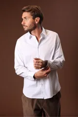 Camisa blanca de manga larga con cuello clásico y cierre frontal con botones.