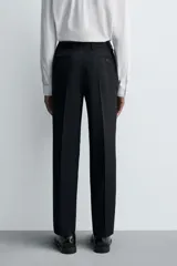 Pantalón de traje regular fit confeccionado en tejido de lana. Presenta bolsillos frontales, bolsillos traseros de vivo con botón y cierre frontal con cremallera y botón.