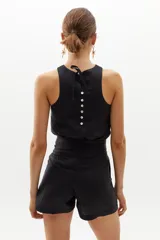 Short de lino negro con cintura alta, pinzas delanteras, bolsillos laterales y cierre frontal con gancho metálico.