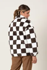 Campera de textura tipo peluche con diseño de cuadros damero en color marrón y blanco. Presenta cuello alto, cierre frontal completo y bolsillos laterales.