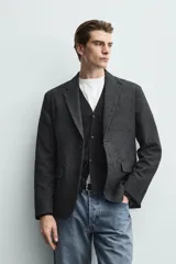 Blazer regular fit de bouclé con diseño pata de gallo en tonos oscuros, solapas de muesca, cierre de un botón y bolsillos con solapa en la cadera.