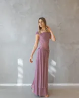 Vestido largo color malva con escote barco, cuerpo ajustado y falda fluida con detalle de drapeado y fruncido en la cintura.