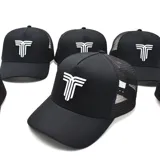 Gorro negro tipo trucker con paneles frontales rígidos y paneles traseros de malla. Presenta un logo bordado en blanco en el frente.