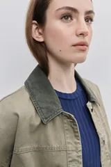 Campera de gabardina tostada, con cuello camisero de pana marrón, cierre frontal de botones metálicos y bolsillos delanteros aplicados con solapa.