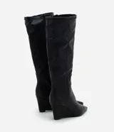 Bota de caña alta Satinato en color negro, confeccionada en material sintético con acabado liso. Presenta un diseño de punta fina y tacón tipo anabela, con una estructura ajustada a la pierna.