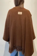 Ruana de lana color beige, tejida en punto acanalado con terminación de flecos en los bordes.