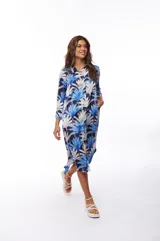 Vestido camisero midi con estampado de hojas de palmera en tonos azul, blanco y negro. Tiene cuello camisero, mangas largas con puños abotonados, cierre frontal con botones y bolsillos laterales.