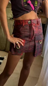 Falda corta de cuero en tono marrón con acabado desgastado, presenta bolsillos laterales grandes e irregulares y costuras decorativas visibles.