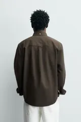 Camisa de corte regular fit confeccionada en tejido de algodón con diseño de rayas verticales. Presenta cuello abotonado, manga larga con puños abotonados, bolsillo plastrón en el pecho y cierre frontal con botones.