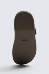 Sandalia negra de dos tiras anchas ajustables con hebillas metálicas cuadradas. Presenta una plantilla anatómica y suela plana a tono.