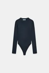 Body de manga larga con cuello redondo, confeccionado en una mezcla de algodón y modal. Presenta cierre inferior con botones a presión.