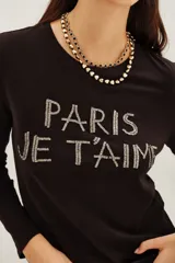 Remera de manga larga color negro, confeccionada en algodón, con estampa frontal bordada en hilo metalizado con la frase 'PARIS JE T'AIME'.