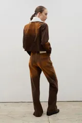 Pantalón de tiro alto confeccionado en pana, con corte recto y efecto gastado en degradé que transiciona de tonos oscuros a ocre. Presenta un cierre frontal con botones visibles y costuras a contratono.