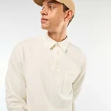 Buzo de manga larga color blanco roto, con cuello polo y tapeta de tres botones. Posee un bolsillo de parche en el lado izquierdo del pecho.