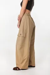 Pantalón cargo de tiro alto, color beige, con silueta amplia de pierna ancha, pretina elastizada en la espalda y bolsillos utilitarios laterales con solapa.